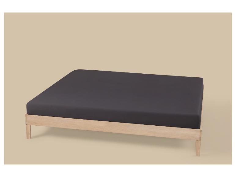Houten bedframe met donkergrijs matras op een beige achtergrond.