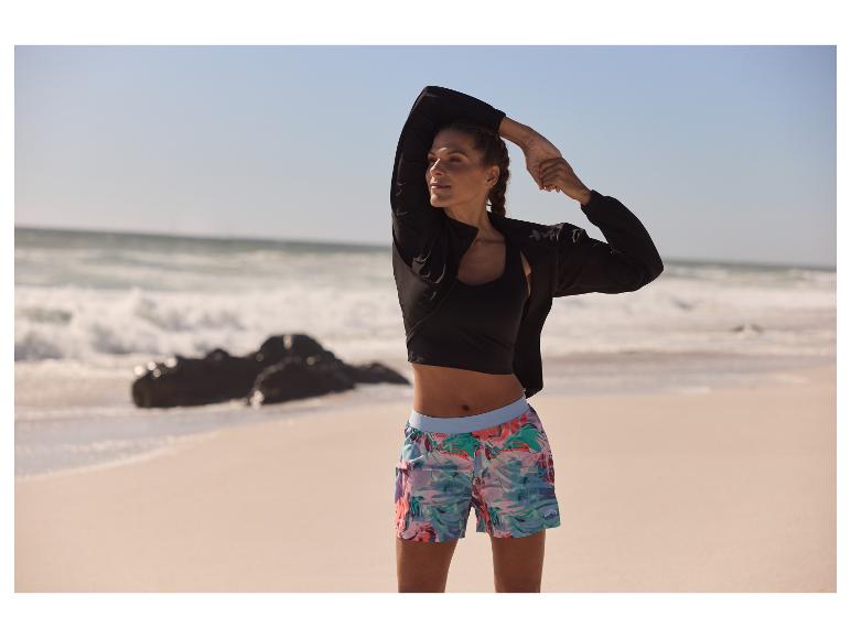Sportkleding: jas, top en bloemen shorts op het strand.