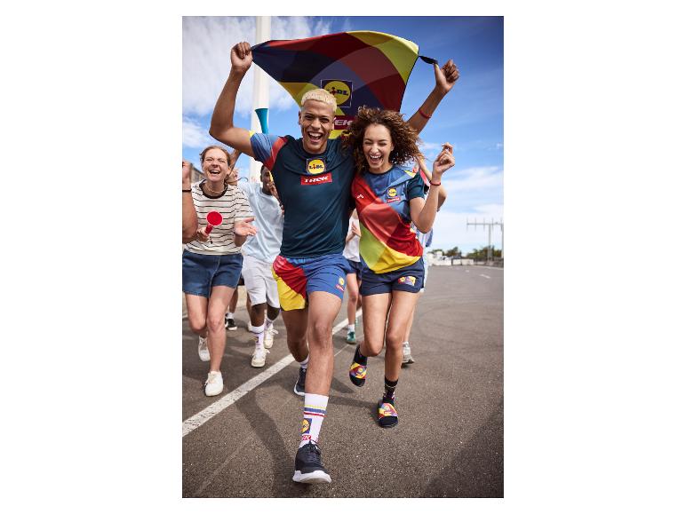 Een groep mensen rent en juicht, gekleed in kleurrijke sportkleding met patronen.
