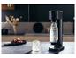 Bruiswatermaker met een fles bruiswater, een glas ijswater en druiven.