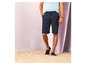 Man in blauwe shorts en sandalen op het strand.