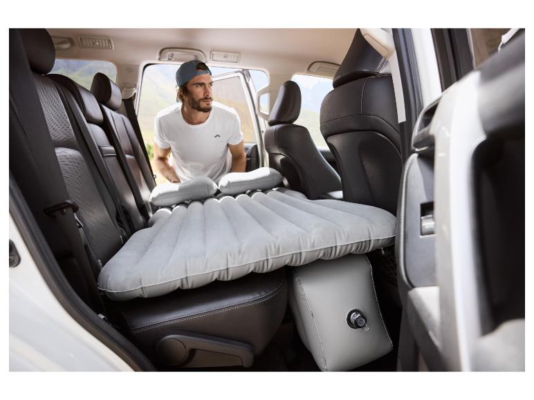 Man in auto met opblaasbaar matras en kussens.