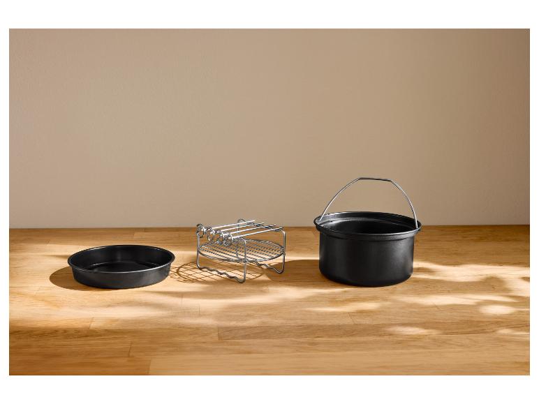 Ronde pan, rek en pot met handvat voor airfryer op een houten tafel.