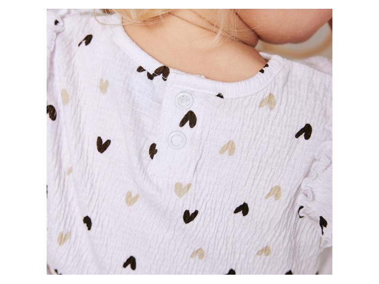 Babyjurk met hartjesprint, beige en zwarte tinten.