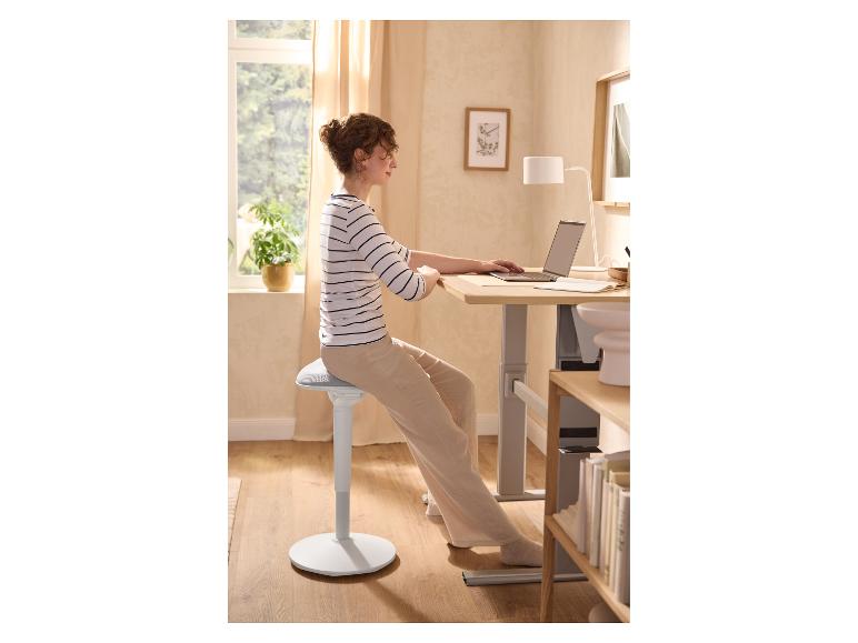 Vrouw gebruikt LIVARNO® Stehhilfe bij een verstelbaar bureau met laptop.