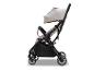 Lichte en compacte beige kinderwagen met zwart frame, van de zijkant gezien.