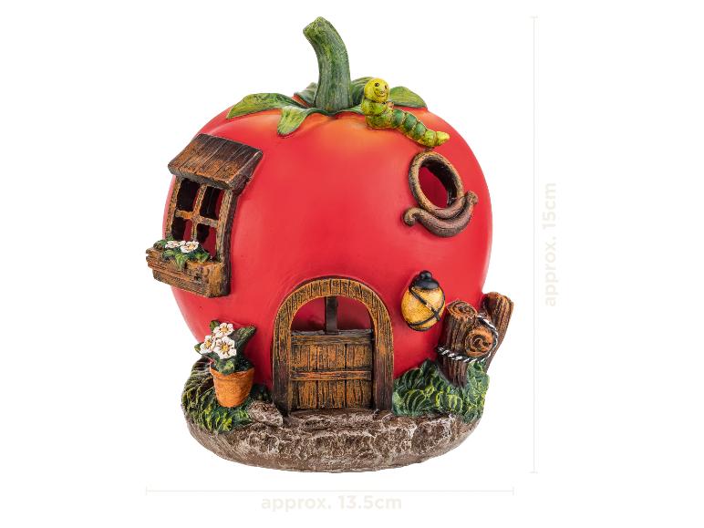 Decoratief tomatenvormig sprookjeshuis met raam, deur, bloemen en een rups bovenaan.