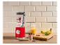 Rode blender met bessen en yoghurt, omringd door fruit en sap op een houten aanrecht.