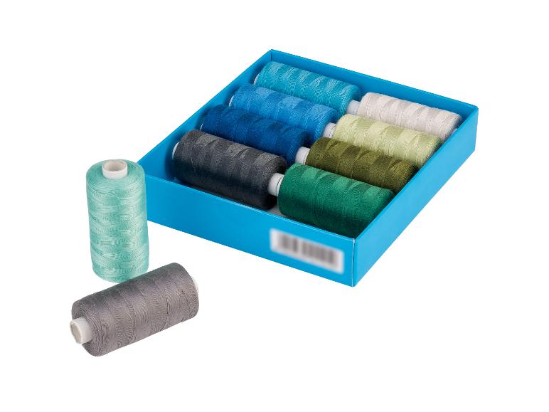 Een set kleurrijke naaigarens in een blauwe doos, met twee spoelen ernaast.