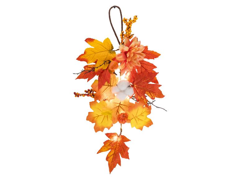 Herfstkrans met bladeren, bessen, bloemen, katoenen details en verlichting.