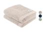 Twee gevouwen beige handdoeken met een klein label, vergezeld van kleurstalen.
