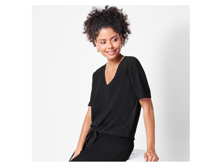 Een vrouw draagt een zwarte top en broek.