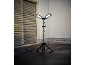 Statiefbouwlamp met twee verlichte panelen op asfalt naast een garagedeur en bakstenen muur.
