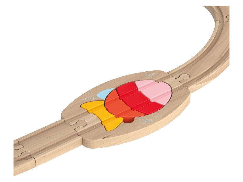 Een houten treinbaan met een kleurrijke visvormige puzzelinzet.