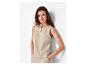 Vrouw in mouwloze beige top en broek, met gouden armband en ketting.