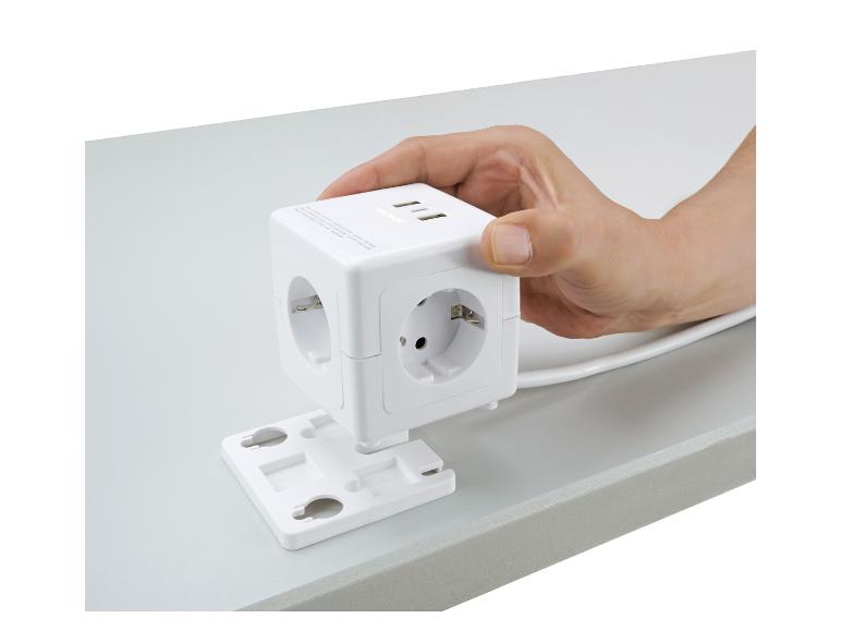 Witte TRONIC stekkerdoos met USB-poorten, vastgehouden door een hand op een tafel.