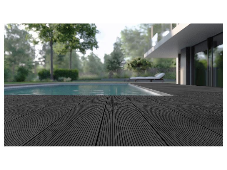 Donker composiet terras bij een zwembad met ligstoel en modern huis op de achtergrond.