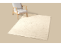 Fauteuil en crèmekleurig vloerkleed met golvend patroon op beige achtergrond.
