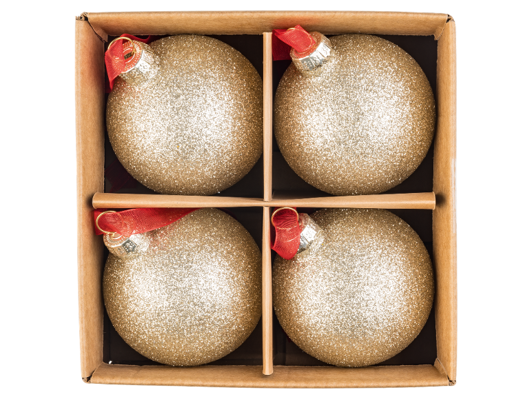 Vier glimmende gouden kerstballen met rode linten in een kartonnen doos.