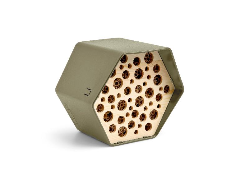 Zeshoekig insectenhotel in kaki kleur met houten interieur en gaten.