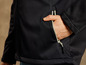 Een close-up van een zwarte softshell jas met een zak met rits.