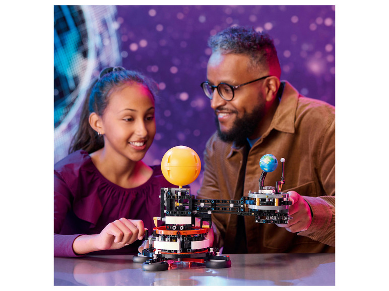 Een vader en dochter bouwen een LEGO Technic model van het zonnestelsel.