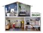 Een groot poppenhuis met meerdere kamers, meubels en een pop.
