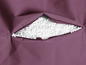 Een paarse beanbag met witte EPS-korrels zichtbaar door de open rits.
