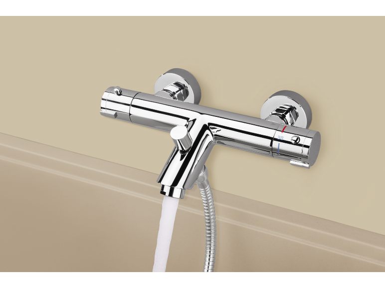 Chromen thermostatische bad-douchemengkraan met water dat in een bad stroomt.