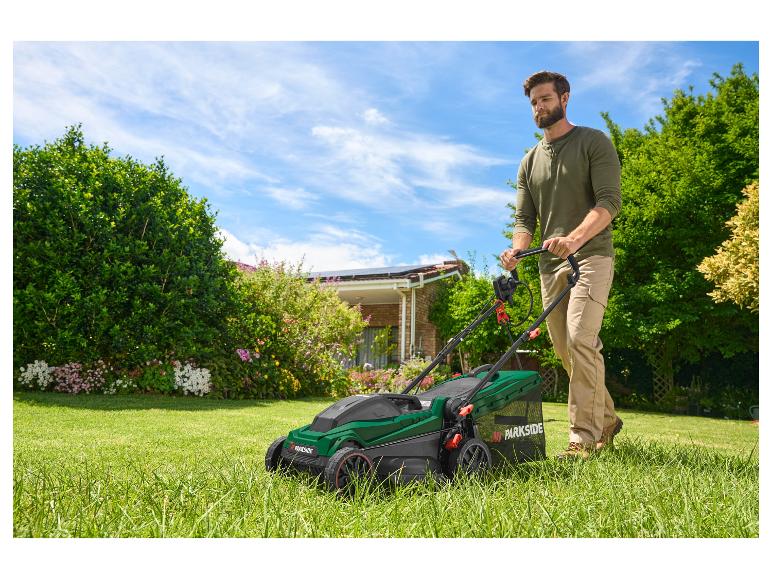 Een man maait het gras met een Parkside grasmaaier.