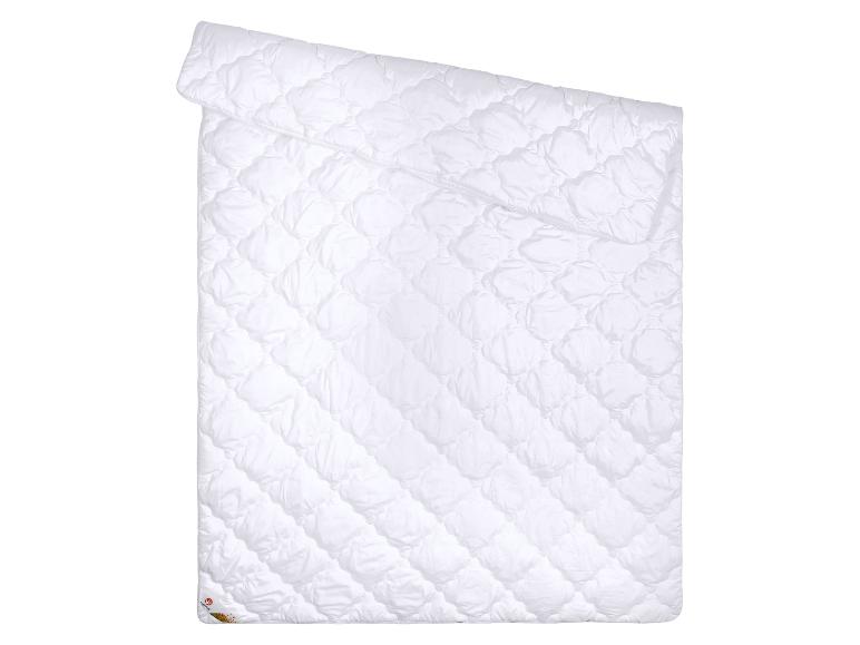 Wit dekbed met gewatteerd patroon, gevouwen op een witte achtergrond.