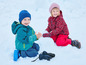 Twee kinderen in winterkleding spelen in de sneeuw.