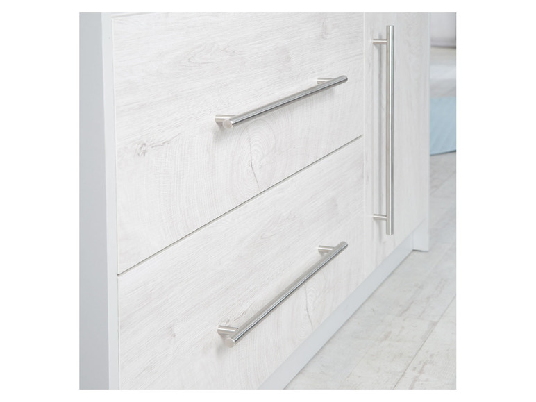 Witte kast met drie lades met zilveren handgrepen.