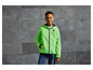 Een jongen draagt een groene windjack met capuchon en een logo.