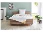 Bed met wit dekbed en kussen, nachtkastje en plant in een lichte slaapkamer.
