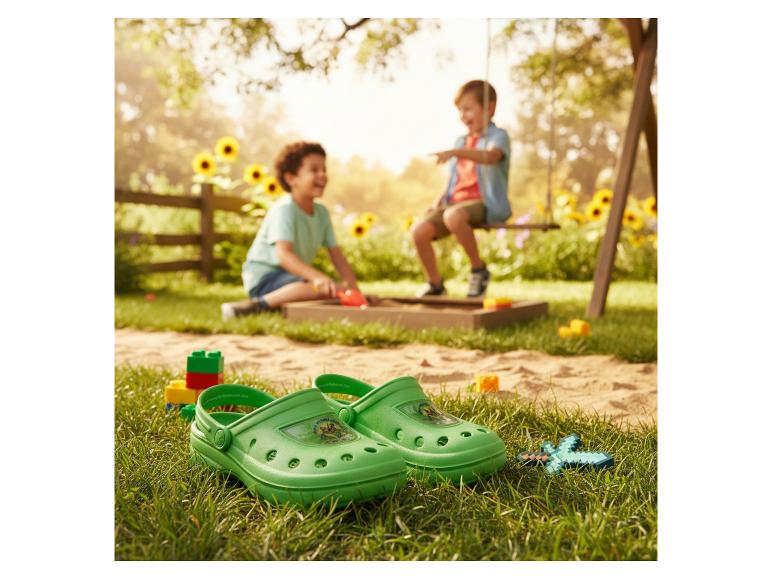 Groene klompen en bouwblokken op gras, met kinderen spelend in een zandbak en op een schommel.