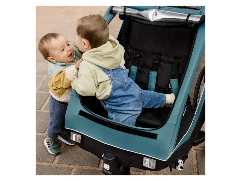 Twee kinderen spelen in een turquoise Hauck Dryk Duo fietskar.