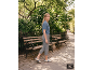 Vrouw in blauw gebreid shirt, grijze broek en sneakers in een park.