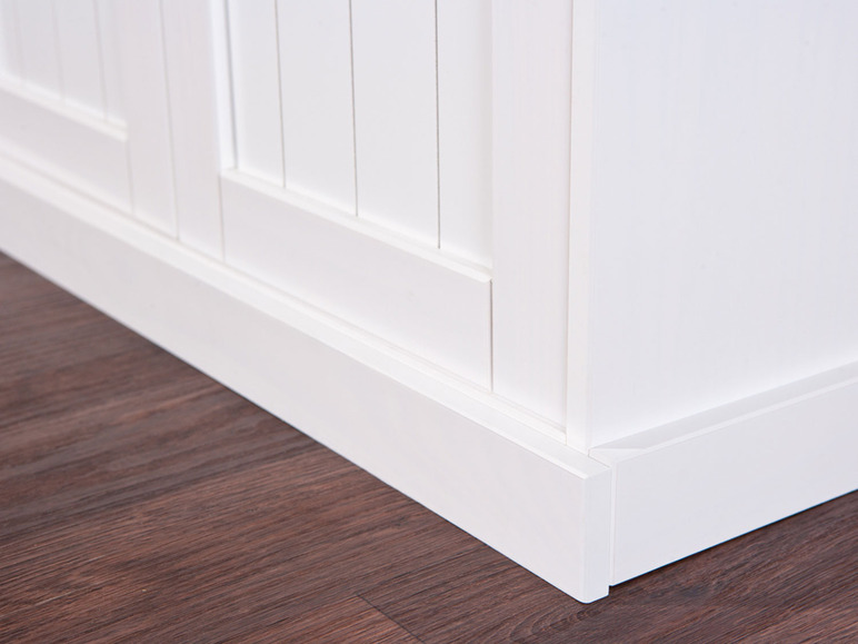 Witte kast met paneeldeuren op een houten vloer