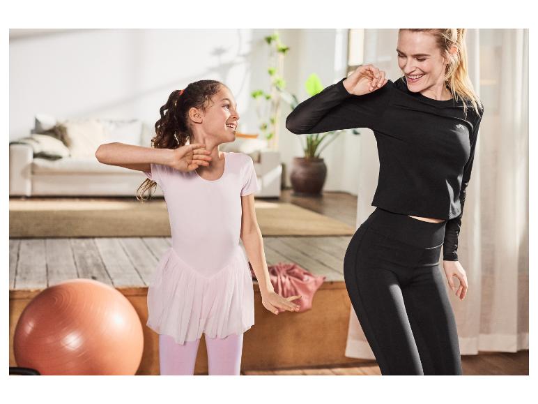 Vrouw en meisje sporten thuis in sportkleding.