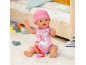 Babypop in roze romper en muts, met speen, zittend op een vloerkleed.