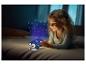 Lachend meisje in bed met een nachtlampje projector die sterren en een maan projecteert.