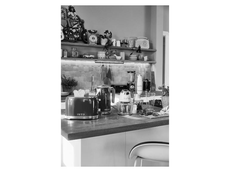 1973-stijl broodrooster, waterkoker en andere keukenapparatuur op een houten aanrecht.