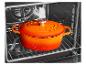 Oranje gietijzeren pan met deksel in een oven