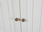 Witte kast met twee deuren en houten knoppen.