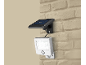Op zonne-energie werkende LED-beveiligingslamp met bewegingssensor op bakstenen muur.