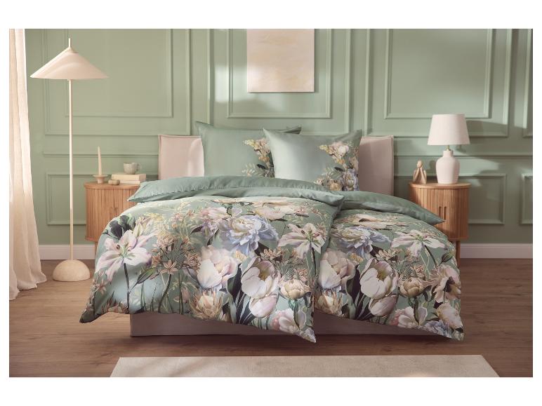 Slaapkamer met bloemendekbedovertrekset, saliegroene muren en houten meubels.