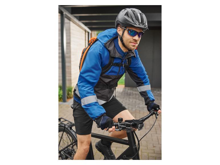 Man in blauwe fietsjas, helm en zonnebril op een zwarte fiets.