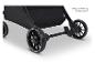 Close-up van de wielen en het rempedaal van een kinderwagen, met een zwarte opbergmand.