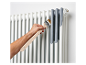 Iemand schildert een radiator grijs.